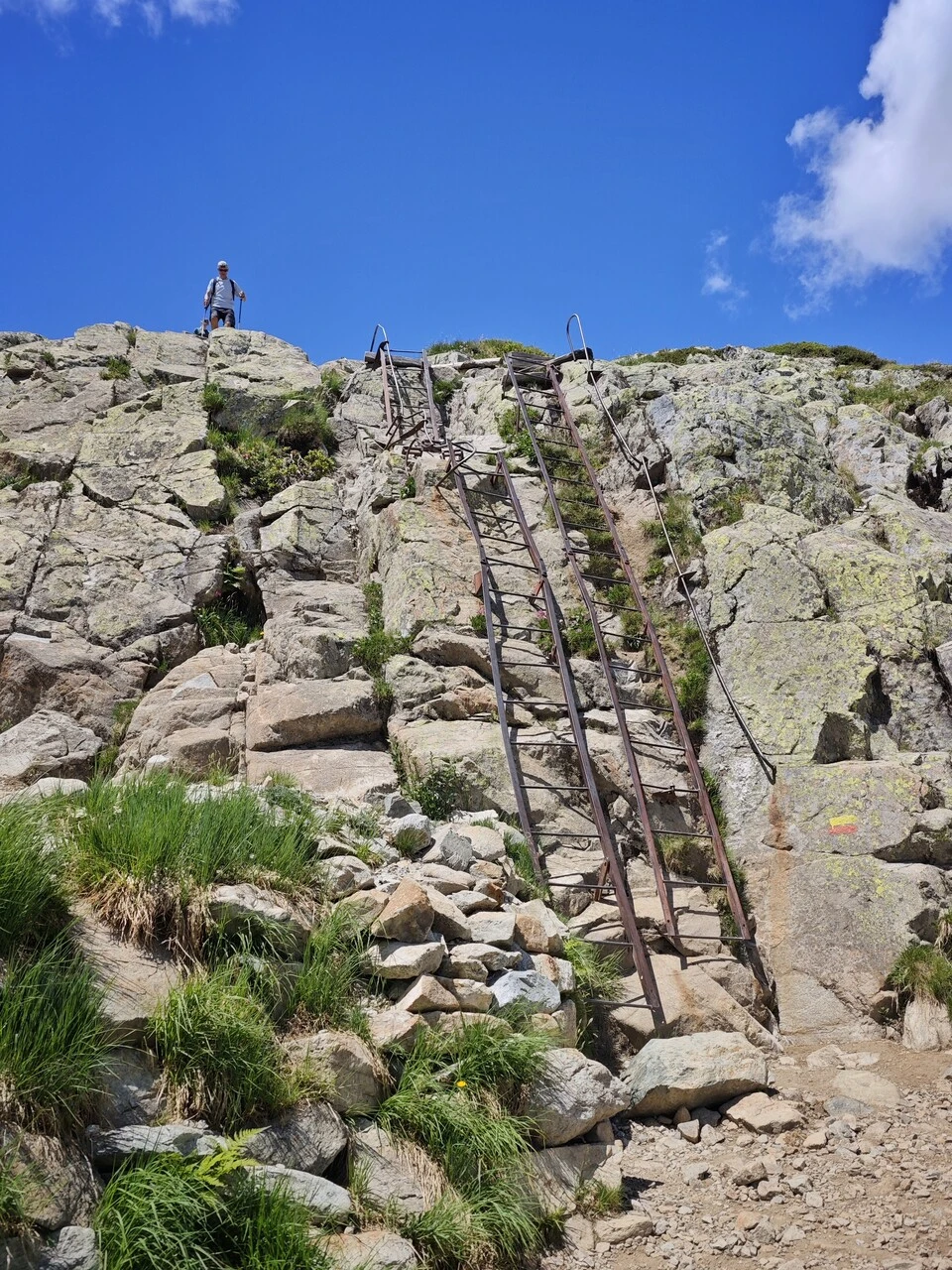 Un senderista en lo alto de las escaleras metálicas de Trè-le-Champ